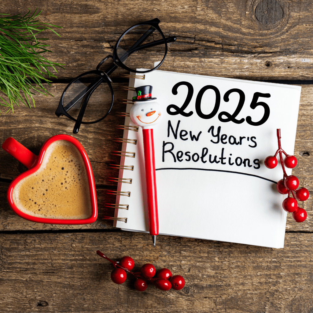 New Year Resolutions 2025 written on notebook sitting on wooden desk